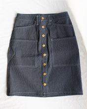 Load image into Gallery viewer, Old fashion standards button skirt in formal ticking. This skirt features round brass buttons running down the middle and an extra pair of big pockets in the front at thigh height, in addition to classic front and back pockets. The &quot;formal ticking&quot; fabric is dark navy based with white ticking that forms fine vertical stripes. Again... 6 spacious pockets in total!! - flat front
