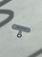 Ina Seifart - Phone Case Adapter - a grey insert that goes  between your phone and phone case, with a little black loop for attaching the phone necklace to