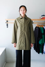 Filippa K - Cassie Car Coat - Laurel Green - Front. This structured thigh length spring-summer coat features a visible button at the top. 