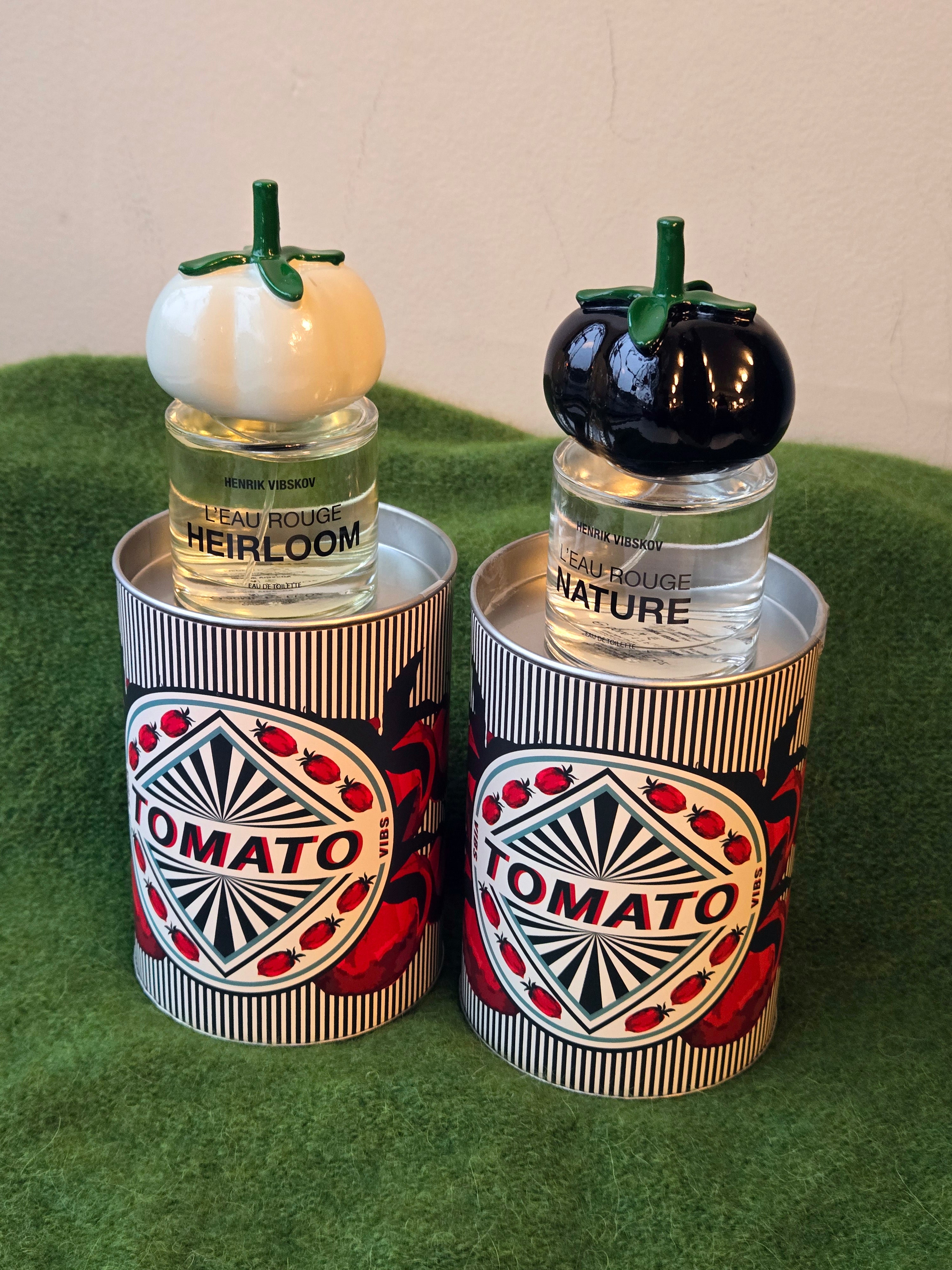 Two small bottles with tomato-themed designs on a green surface.