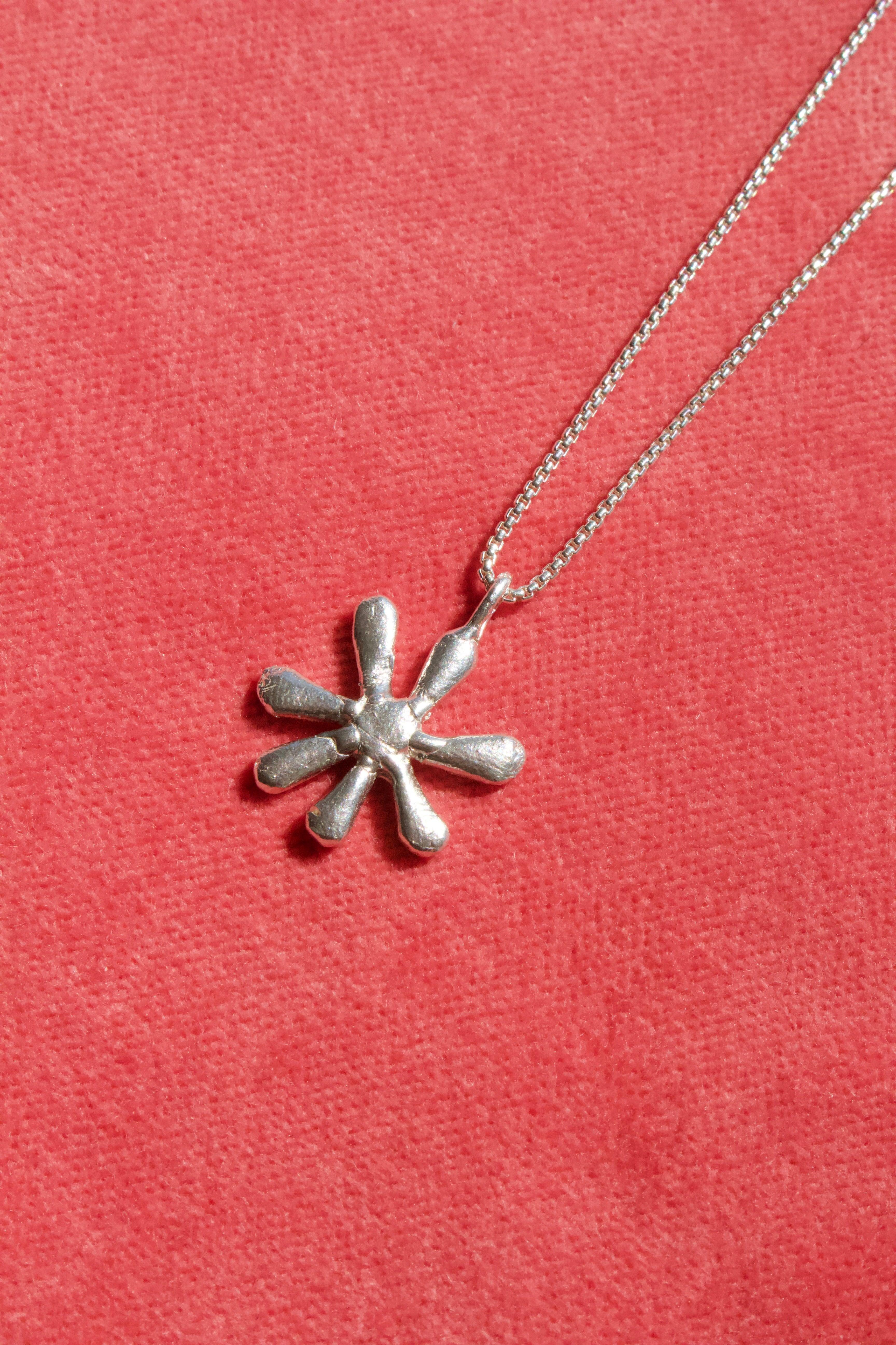 A close up of the Daisy pendant from Erica Leal, in this photo you are able to see the natural finger prints left behind by the artist who makes this necklace, created through the initial hand molded wax stage. 