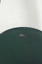 Load image into Gallery viewer, A.P.C Demi-Lune Bag in Vert Sapin - Eugene Choo - Women&#39;s Accessories: a close up of the gold toned namesake embossed stamp on the centre front of the purse
