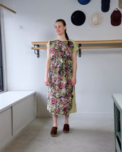 Load image into Gallery viewer, anntian - Simple Dress - Pressed Flowers (K) - front - this image depict our staff jamie wearing the anntian simple dress in print k. the simple dress is relaxed and features a pressed flower print on both the front and back. the fabric around the print is in a pale green, and the print is of dense pressed flowers in various rich colors
