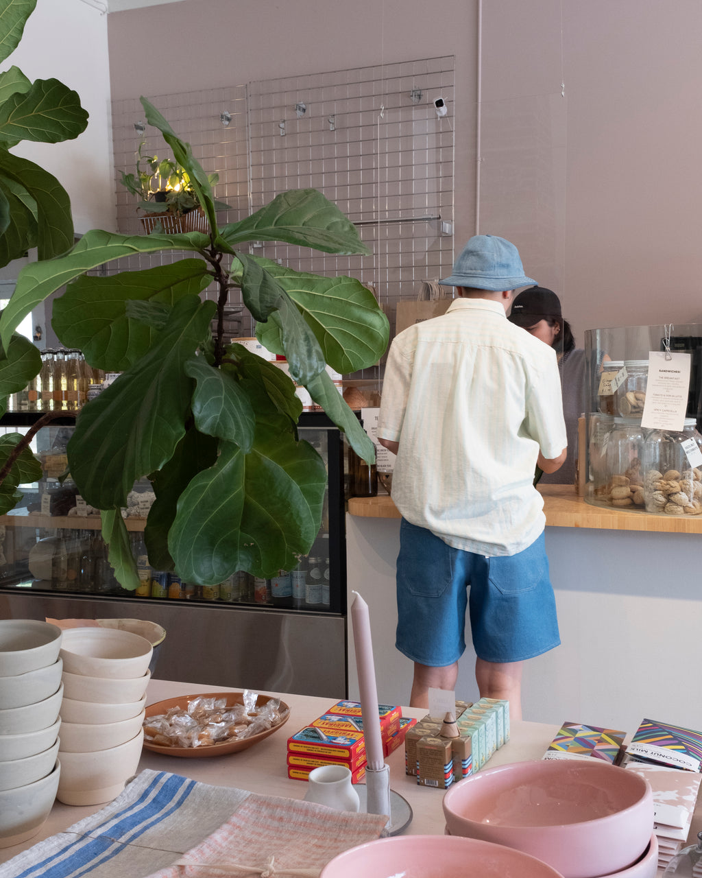 Macrina wearing the Minimum Thao LS Shirt in icy morning (light blue and cream vertical stripes), styled with Old Fashion Standards New Short and Bucket hat in Light Denim - back (paying for our coffees)