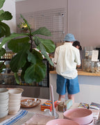 Macrina wearing the Minimum Thao LS Shirt in icy morning (light blue and cream vertical stripes), styled with Old Fashion Standards New Short and Bucket hat in Light Denim - back (paying for our coffees)