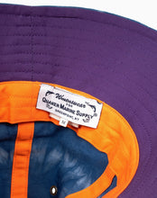 Load image into Gallery viewer, W&#39;menswear mekong sailing hat - inside. This hat&#39;s inner rim is purple, and is lined with orange fabric to compliment the indigo dye.
